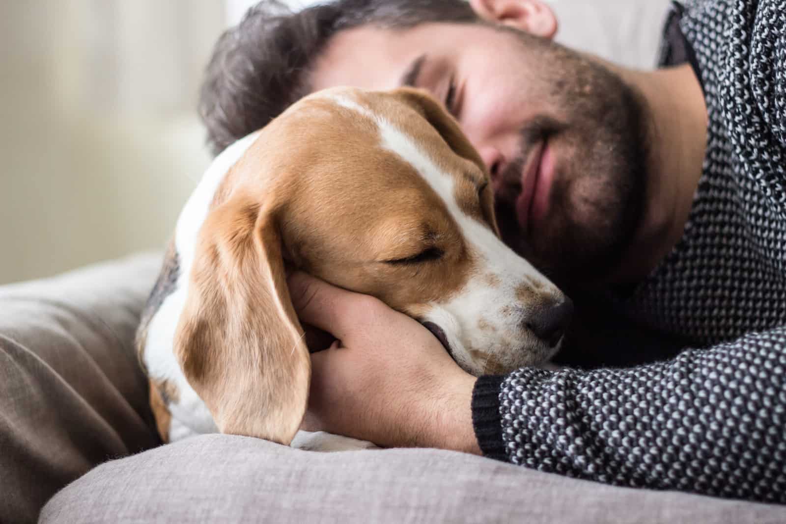Junger Mann, der mit einem Hund schläft