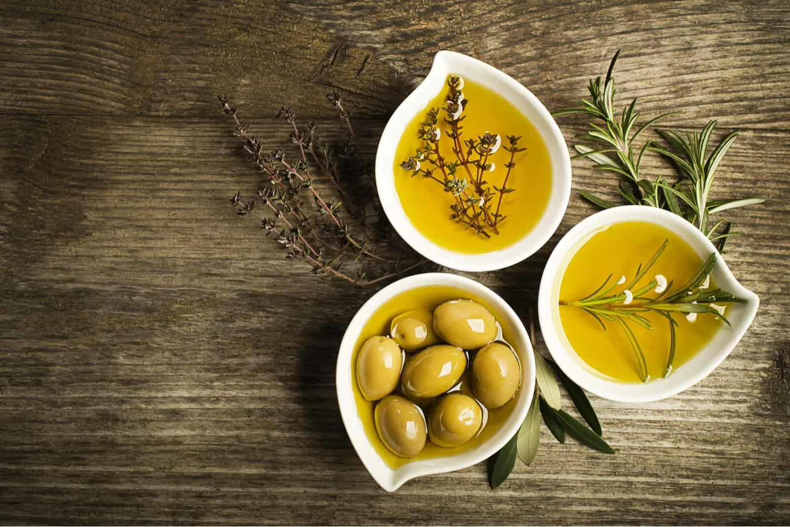 Olivenöl in Schalen auf einem Holztisch