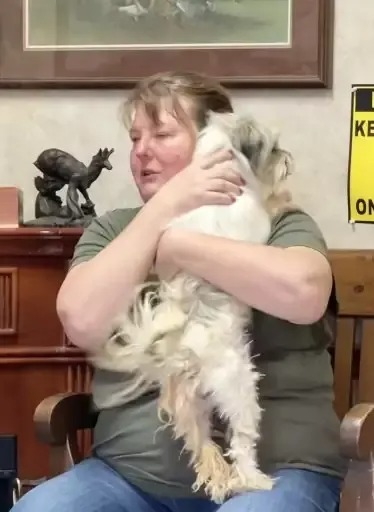 Eine Frau haelt einen Hund in den Armen
