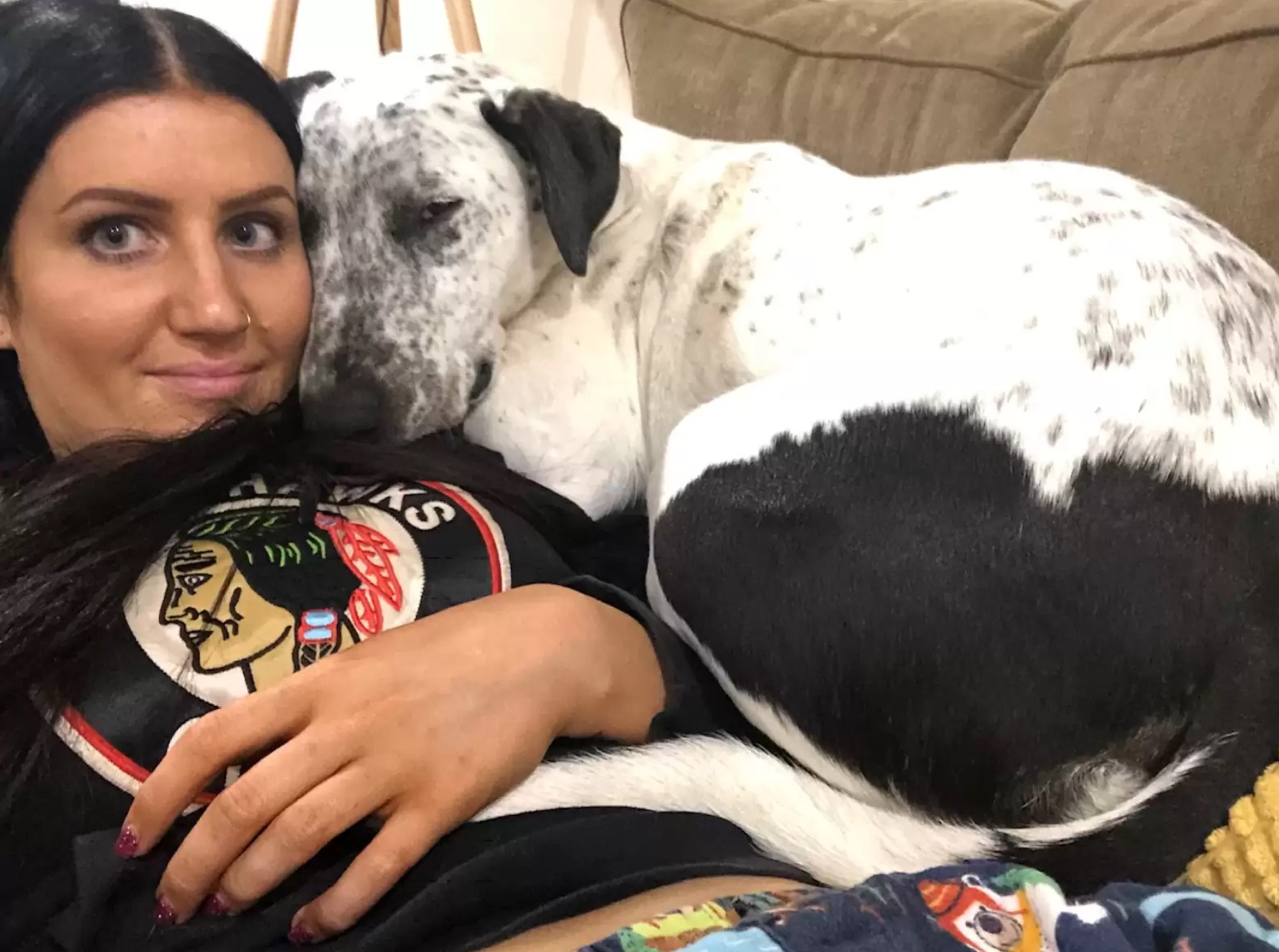 Eine Frau und ein Hund liegen zusammen auf der Couch