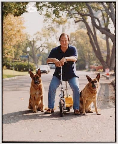 James Belushi mit zwei Schaeferhunden auf einer Straße