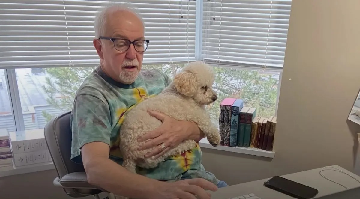 Mann haelt Hund in den Armen