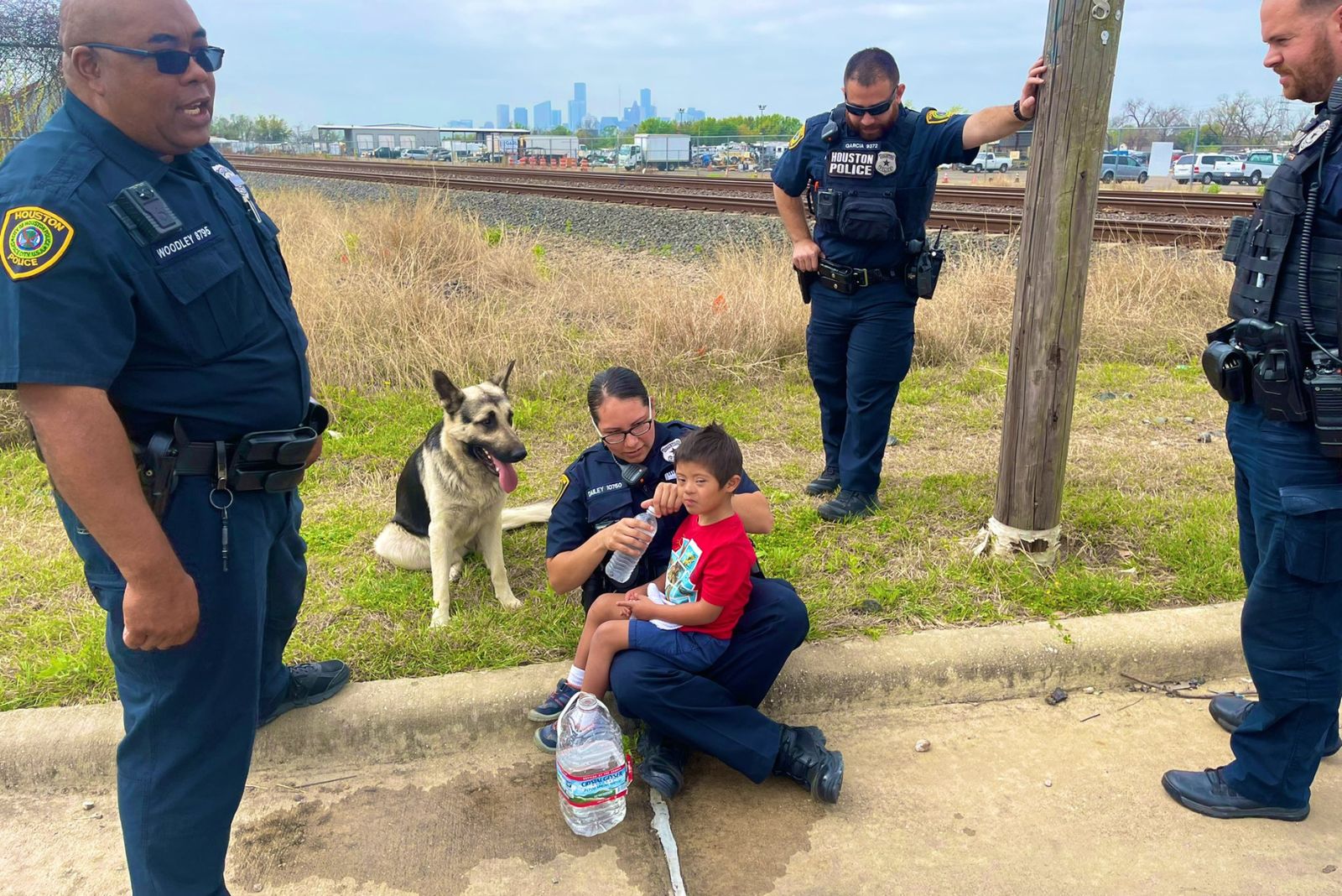 Polizeibeamte mit einem Jungen und einem Schaeferhund