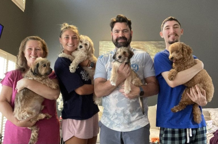 Familie haelt vier Hunde in den Armen