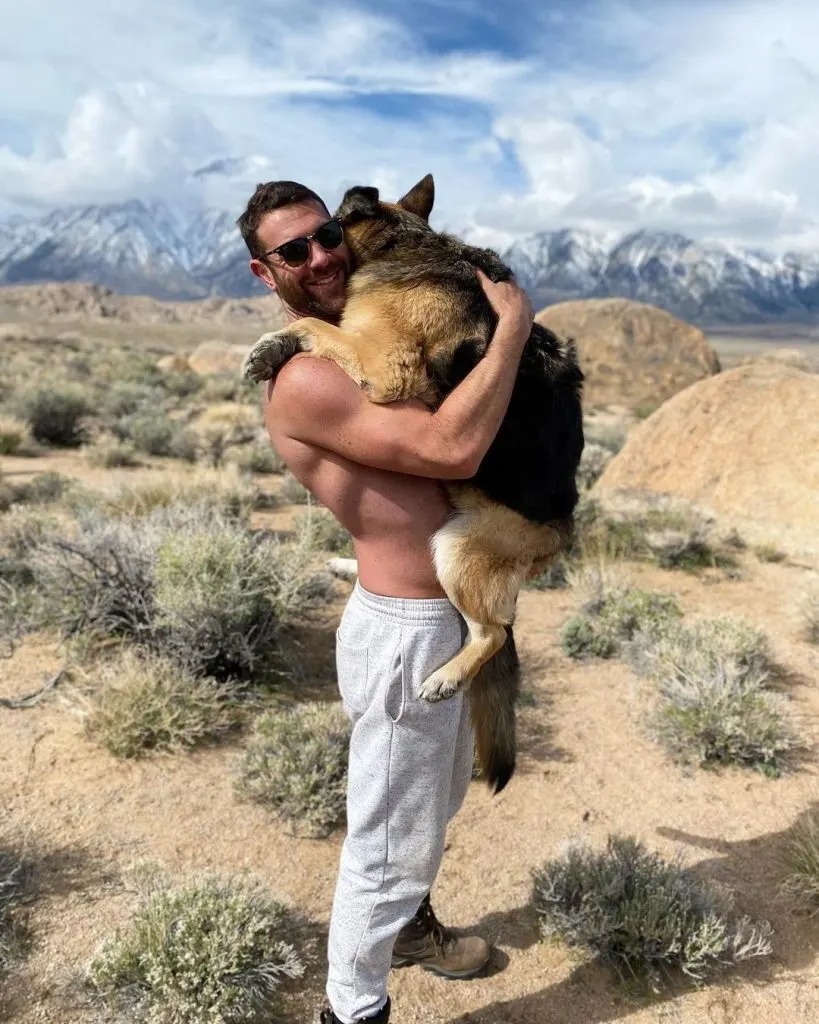 Mann traegt Hund in den Armen